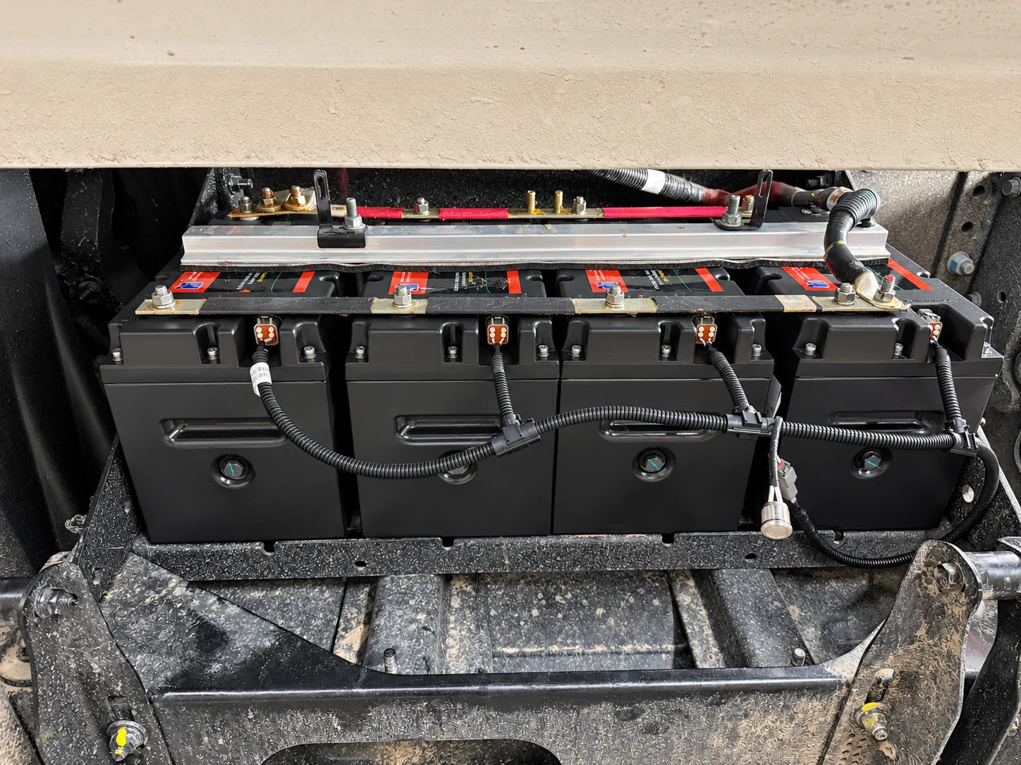 Four dual-purpose batteries secured with retaining rails and a communication harness