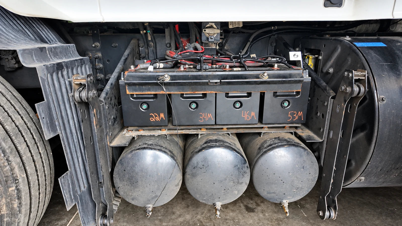 Four batteries installed above three air tanks beside a truck fuel tank