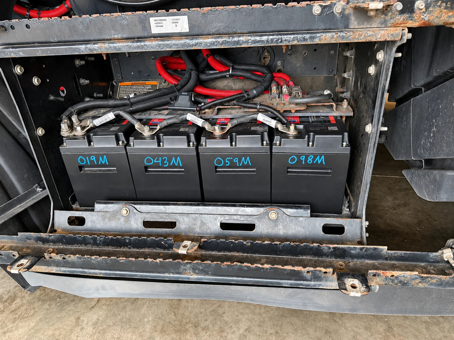 Four batteries with blue service markings and red cable looms