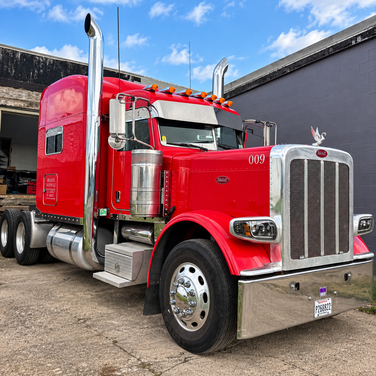 A red Peterbilt sleeper truck parked in an industrial yard